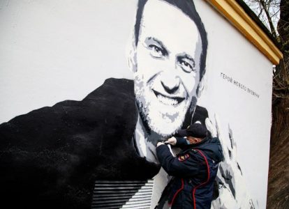 Сотрудник полиции соскребает краску с граффити Навального